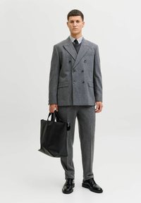 Szary wełniany garnitur z marynarką dwurzędową i dopasowanymi spodniami. Czarna skórzana torba na ramię. Błyszczące czarne buty. Prosty, nowoczesny design.