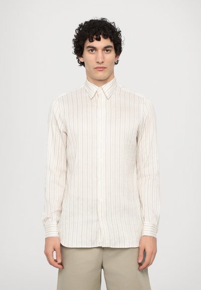 Langærmet skjortebluse i off-white med fine vertikale striber. Stoffet ser let og lidt struktureret ud med en klassisk krave.