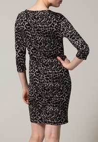 Leopardmönstrad klänning med trekvartsärmar, figurnära passform, mjukt tyg och en färgkombination av svart och beige, utan synliga detaljer eller accenter.