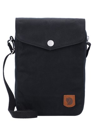 Czarna torba na ramię z klapką i srebrnym zatrzaskiem, regulowanym paskiem oraz małą brązową łatką z logo zwierzęcia w prawym dolnym rogu.