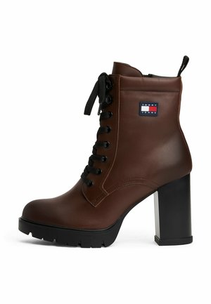 Bottine en cuir marron avec un bout rond, un talon épais noir, un laçage à l'avant et un patch de marque. Présente une finition texturée et une semelle robuste.