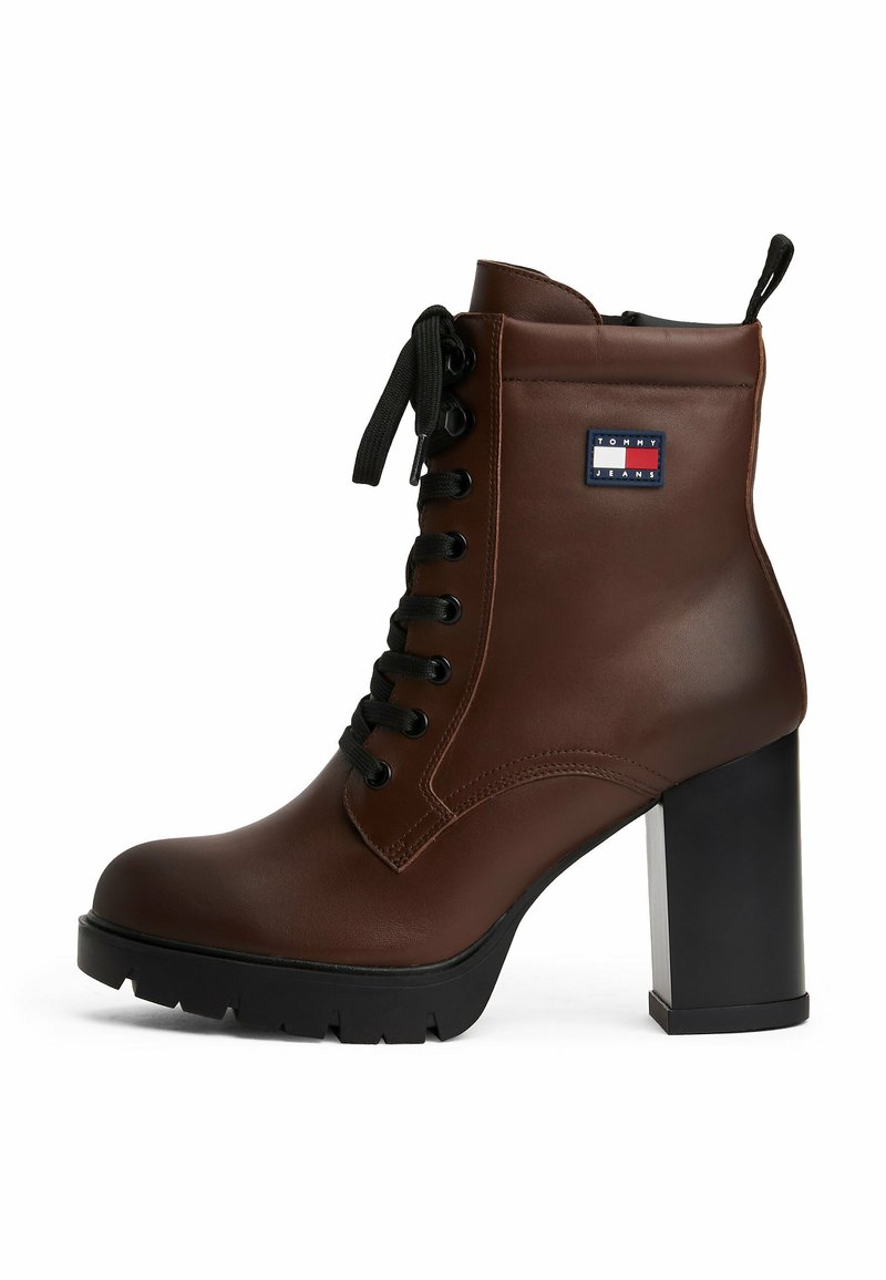 Bottine en cuir marron avec un bout rond, un talon épais noir, un laçage à l'avant et un patch de marque. Présente une finition texturée et une semelle robuste.