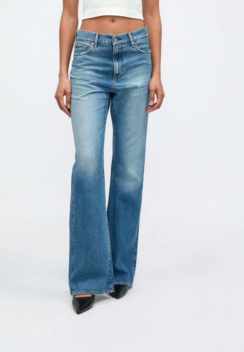 Blugi evazați de culoare albastru deschis, realizați din denim cu o textură decolorată. Au închidere cu nasture, cinci buzunare și talie medie.