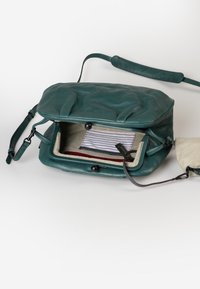 Türkise Lederhandtasche mit strukturiertem Oberflächen, einem Klappverschluss und verstellbarem Tragegurt. Innenausstattung mit gestreifter Fütterung und einem kleinen Fach.