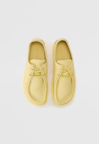 Pantofi slip-on din piele galbenă, cu o formă rotunjită, suprafață texturată și două șnururi decorative pe partea superioară. Talpă ușoară din cauciuc.