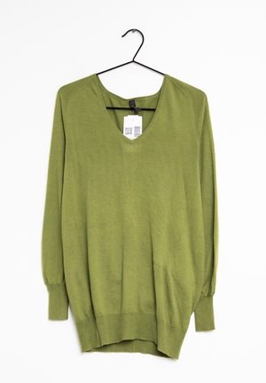 Pull col en V vert olive à manches longues suspendu sur un cintre noir avec une étiquette blanche de prix attachée à l'intérieur de l'encolure.