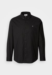 Black button-up shirt made from cotton with a classic collar, long sleeves, and a small CK logo on the left chest.