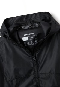 Veste noire pour enfants avec une texture lisse et brillante. Elle possède une capuche, un zip sur le devant et une étiquette indiquant la taille et les propriétés imperméables.