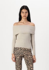Off-the-shoulder ribbed sweater in light beige, featuring long sleeves and a fitted design, paired with leopard print trousers.