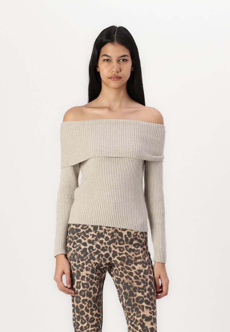 Off-the-shoulder ribbed sweater in light beige, featuring long sleeves and a fitted design, paired with leopard print trousers.