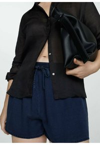 Schwarze durchsichtige Knopfleiste-Hemd, lockere marineblaue Shorts mit elastischem Bund und eine schwarze Lederhandtasche mit strukturiertem Design.