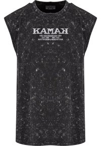 Fekete ujjatlan póló kerek nyakkivágással, texturált, pöttyös mintával és fehér „KAMAK” logóval, amely a mellkason fut végig.