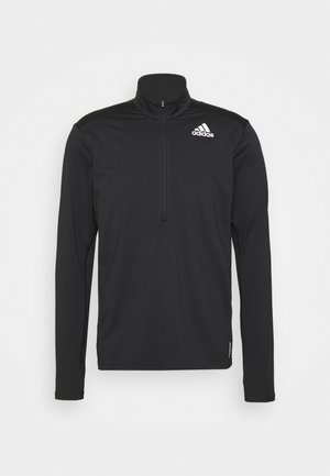Czarna bluza Adidas z długim rękawem, zamkiem na ćwiartkę i białym logo Adidas na lewej piersi, na jednolitym jasnym tle.