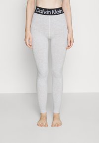 Světle šedé legíny vyrobené z elastického materiálu, s černým pasem značky Calvin Klein a hladkým, přiléhavým designem.