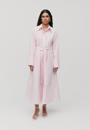 Lange roze shirtjurk gemaakt van een gladde stof. Bevat een kraag, lange mouwen en een bijpassende tailleband. De rok valt tot de enkels.