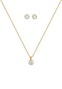 Collana d'oro con un pendente rotondo caratterizzato da una pietra trasparente, accompagnata da orecchini a bottone rotondi abbinati con pietre trasparenti.
