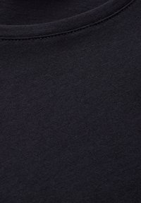 Musta puuvillakangas, jossa on sileä pinta, pyöreä kaula-aukko ja hieno ompelu kauluksessa.