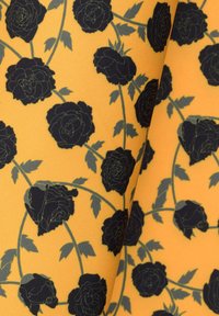 Żółty materiał z kwiatowym wzorem, w którego skład wchodzą czarne róże i zielone liście, o gładkiej fakturze i elastycznych właściwościach.