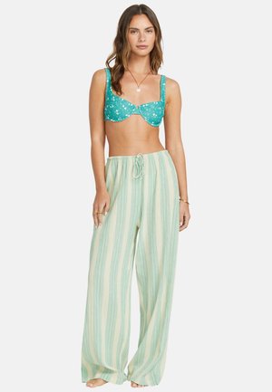 Haut de bikini floral turquoise avec armatures et bretelles réglables, associé à un pantalon large rayé vert clair et crème.