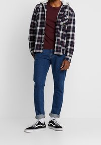 Plaid flannel shirt in navy, white, and burgundy with a hood; maroon crewneck underneath; blue jeans; black and white sneakers.