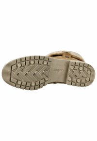 Suela de bota sintética de color marrón claro con material de goma texturizado, que presenta surcos prominentes y un logo en una sección lisa.