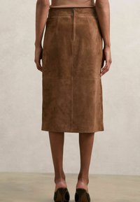 Gonna in suede marrone con vestibilità dritta, cuciture visibili e zip centrale sul retro. Lunghezza al ginocchio con una texture liscia e morbida.