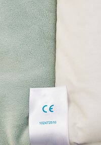 Weiches, mintgrünes Fleece-Stoff auf einer Seite und weiße Baumwolle auf der anderen, mit einem Pflegeetikett mit CE-Kennzeichnung und Produktnummer.