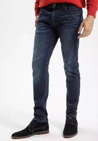 Ciemnoniebieskie dżinsy wykonane z denimu, dopasowany kr�ój, prosta nogawka, z delikatnym przetarciem i pięcioma kieszeniami, w zestawieniu z czarnymi zamszowymi butami.