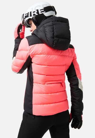 Padded ski jacket in bright pink and black, featuring a hood, zippered pocket, and black gloves. Designed for warmth and mobility.