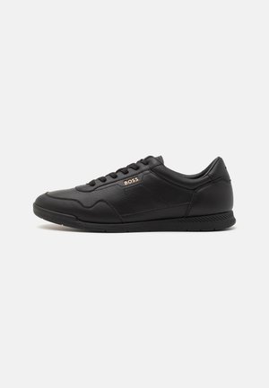 Baskets noires en cuir texturé avec des accents lisses, dotées d'un laçage à l'avant, d'un logo subtil et d'une semelle en caoutchouc.