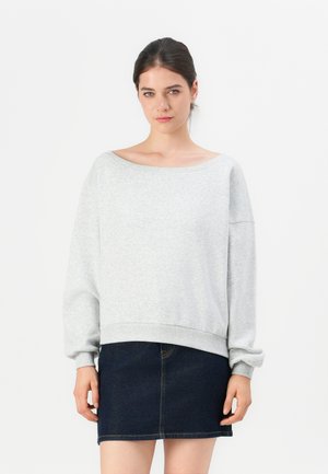 Sweatshirt oversize gris clair avec un large décolleté et un ourlet côtelé, associé à une mini-jupe en denim foncé. Tissu doux avec une coupe décontractée.