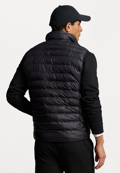 Black puffer vest with a collar, featuring quilted panels. Worn over a black long-sleeve shirt, showcasing a streamlined, casual design.