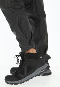 Zwarte wandelschoenen met een gestructureerd oppervlak, vetersluiting en grijze accenten. Duurzame zool met grip, met DRYMAXX-merkvermelding.