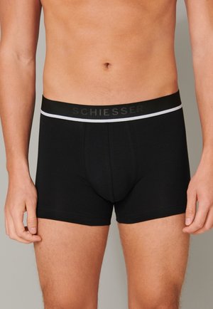 Schwarze Baumwoll-Boxershorts mit einem weichen Bund, auf dem der Markenname "SCHIESSER" in Schwarz und ein weißer Akzentstreifen abgebildet sind.