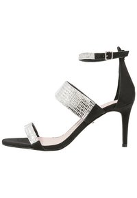 Sandale à talons hauts en suede noir avec des brides en argent réfléchissant, une boucle à la cheville et une semelle lisse. Présente un talon fin et un design ouvert.