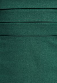 Tamnozeleni materijal s horizontalnim nabranjima, glatke teksture i suptilnim uzorkom tkanja. Uređen dizajn pogodavan za oblikovane odjevne predmete.