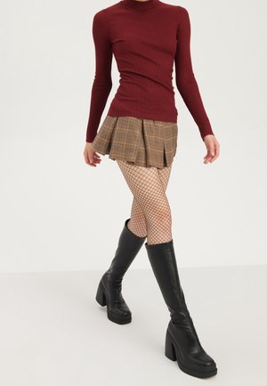 Haut à manches longues bordeaux côtelé, jupe plissée à carreaux marron, bas résille, et bottes à talons noires montant jusqu'aux genoux avec une finition texturée.