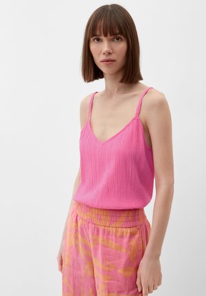Débardeur rose texturé avec des fines bretelles, associé à un pantalon ample avec un motif floral rose et orange.