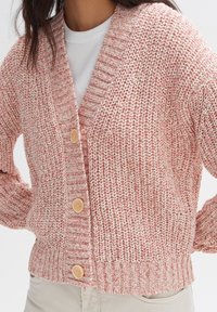 Pletený kardigan v růžové a bílé přízi, s hlubokým výstřihem do V, ribbed manžetami a třemi velkými béžovými knoflíky na přední straně.