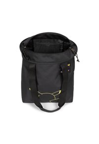 Musta kangaskassi, jossa on keltaisella hahmon ääriviiva etupuolella, kaksinkertaiset mustat kantohihnat ja vetoketjullinen suljenta.