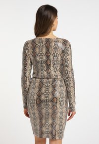 Abito aderente a maniche lunghe con stampa serpente nei colori marrone, beige e nero; presenta un collo rotondo e un tessuto testurizzato.