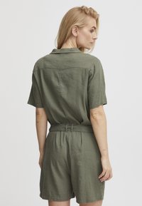 Olivgrüner kurzer Jumpsuit aus Leinen, mit kurzen Ärmeln, umlegebarem Kragen, tailliertem Gürtel und lockerer Passform.