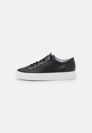 Schwarze Leder-Sneaker mit glatter Textur, runden weißen Ösen, schwarzen Schnürsenkeln und einer weißen Gummisohle. Einfaches und modernes Design.