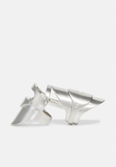 Silberner Metallring mit einem einzigartigen gestuften Design, das glatte und strukturierte Oberflächen, abgerundete Kanten und einen hervorgehobenen Punkt an der Spitze aufweist.