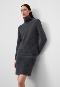 Grijze geribbelde coltrui met een fuzzy, zacht-textuur roksectie. Slim fit en naadloze overgang tussen materialen.