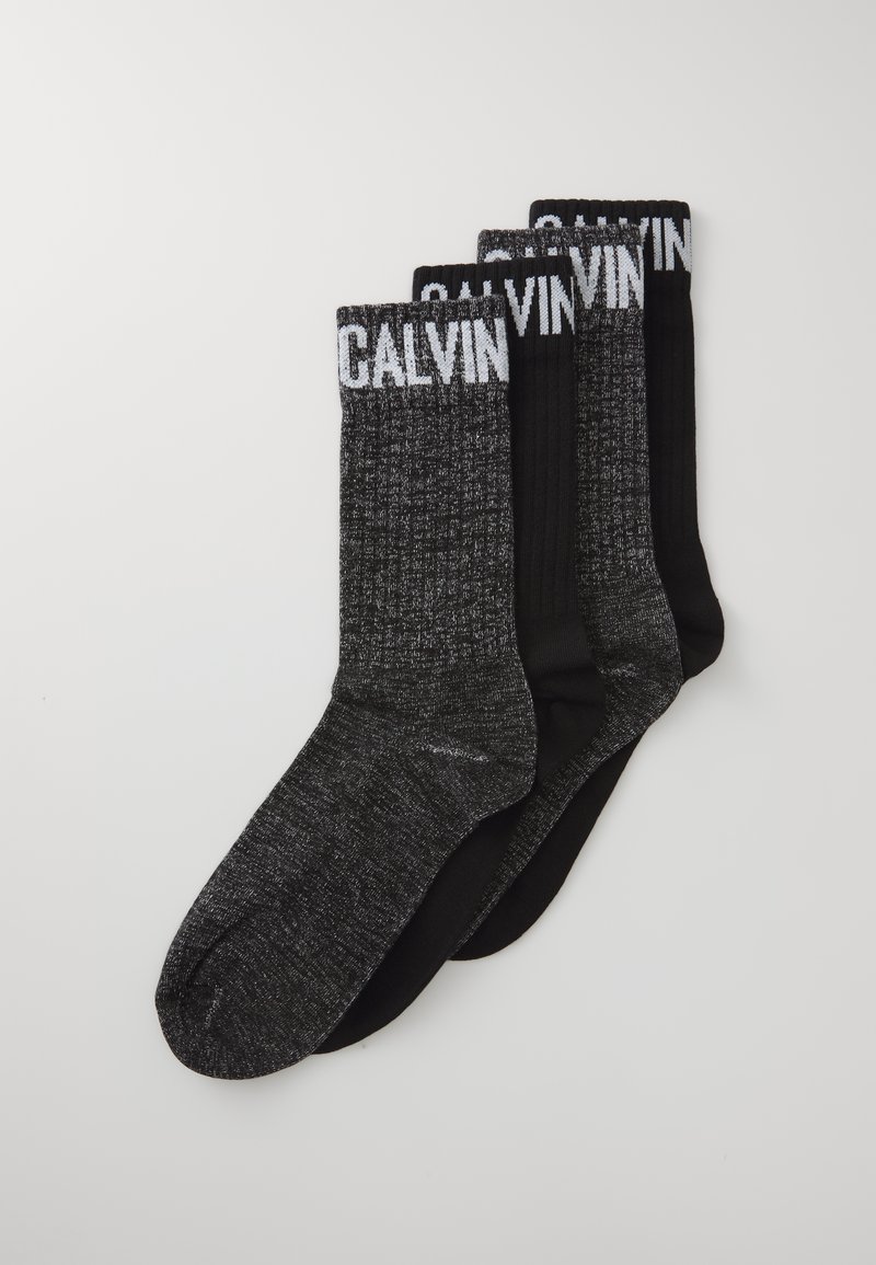 Trzy pary skarpetek: jedna całkowicie czarna, dwie z fakturowanym ciemnoszarym wzorem, z białym logo "CALVIN" na górnych brzegach.