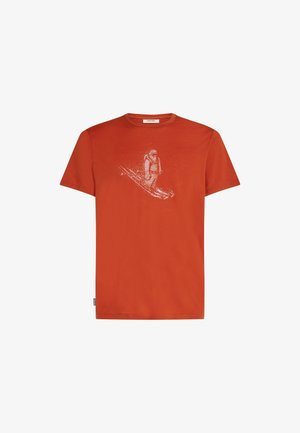 Camiseta de algodón de color naranja brillante, con un gráfico blanco de un esquiador. Cuello redondo, mangas cortas, corte holgado, textura suave.