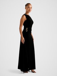 Black velvet maxi dress with asymmetrical neckline, side ruching, and gold button accents on the hips. Smooth texture and flowing silhouette.