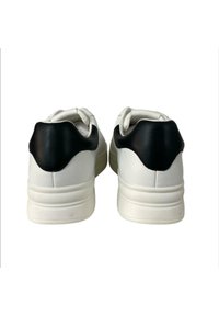 Sneakers bianchi con un accento sul tallone in pelle sintetica nera. Forma arrotondata, texture liscia e suola ammortizzata. Design minimalista.