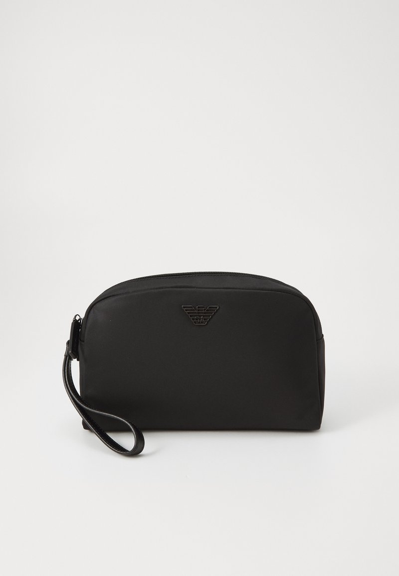 Melnā kosmētikas soma gludā materiālā, ar noapaļotu formu, aprīkota ar rāvējslēdzēja aizdari, plaukstas jostu un izspiesta zīme priekšpusē.